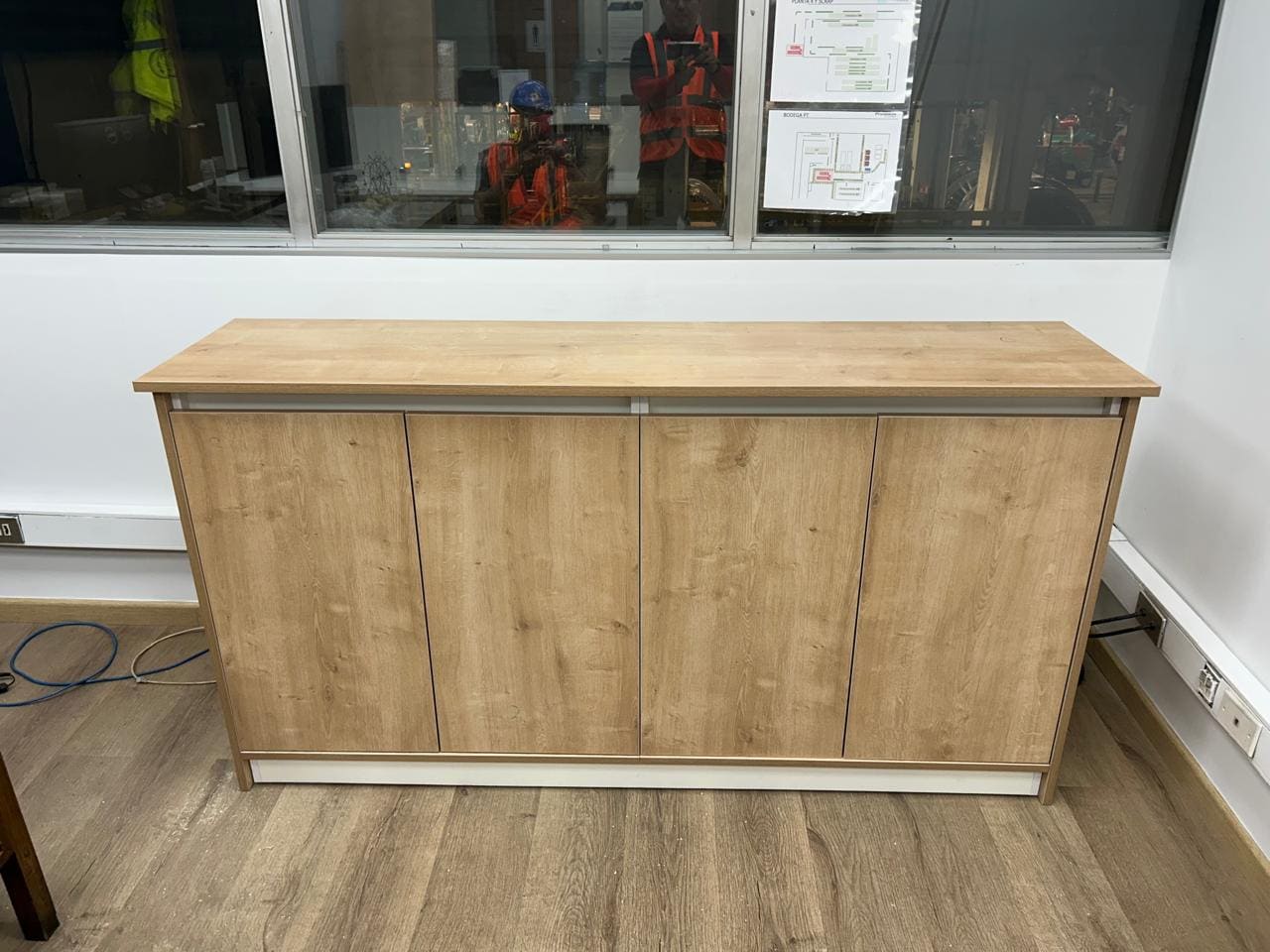 Mueble mesón de recepción en madera clara con zócalo metálico, instalado sobre piso flotante